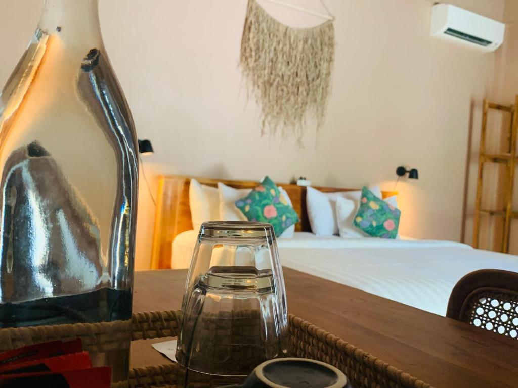 un vase en verre sur une table avec un lit dans l'établissement Anchor Bed & Bread, à Kuta Lombok