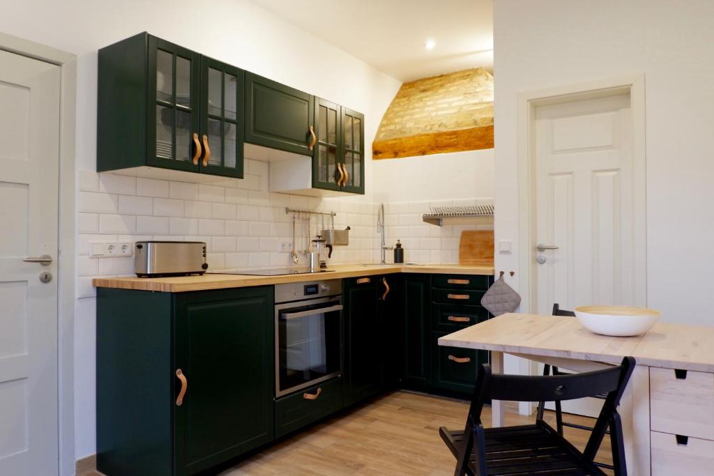 a kitchen with green cabinets and a wooden table at Gut Boltenhof in Fürstenberg