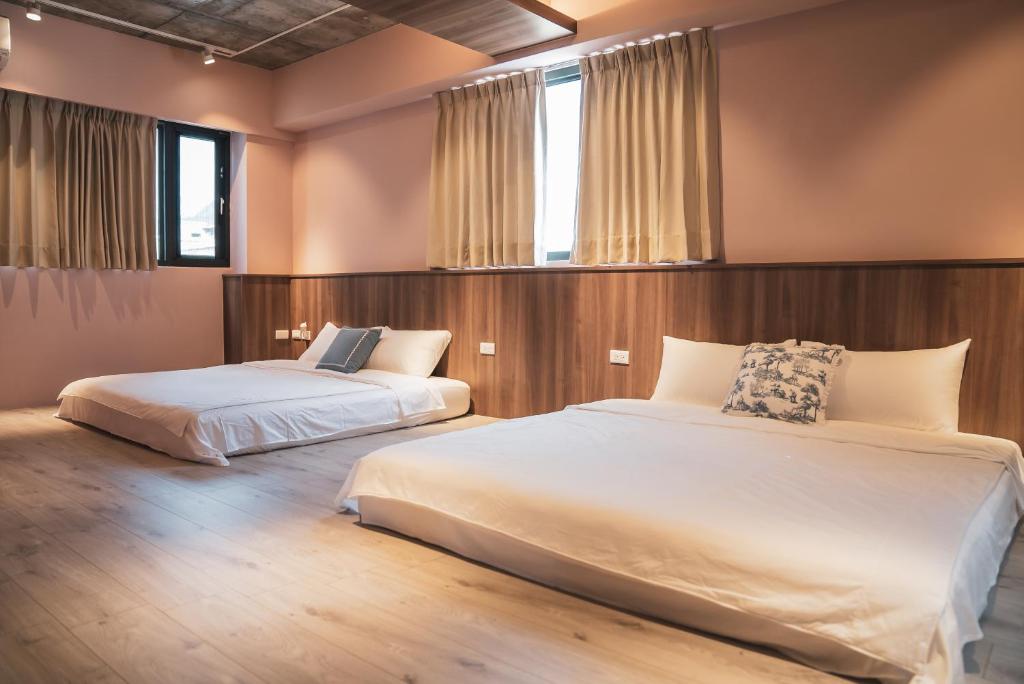 two beds in a bedroom with two windows at Flower Garden B&B in Hengchun