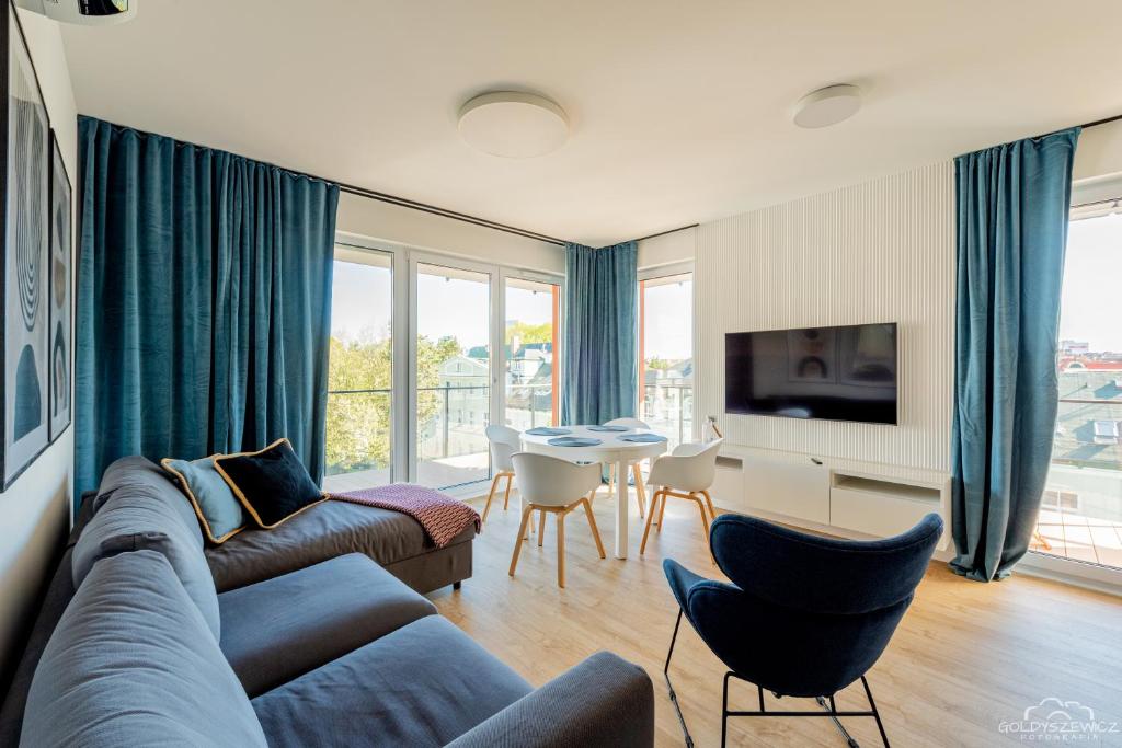 salon z kanapą, krzesłami i telewizorem w obiekcie Horyzont Apartamenty - Wyspa Solna w Kołobrzegu