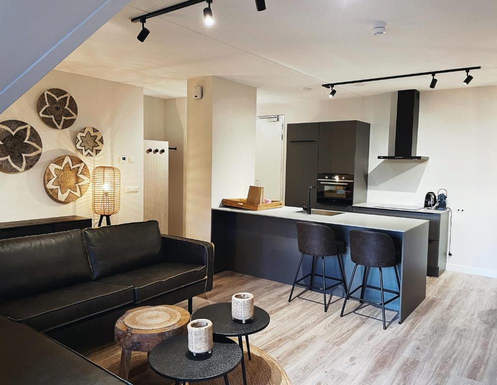 a living room with a couch and a kitchen at Hello Zeeland - Appartement Duno Lodges 6 personen in Oostkapelle