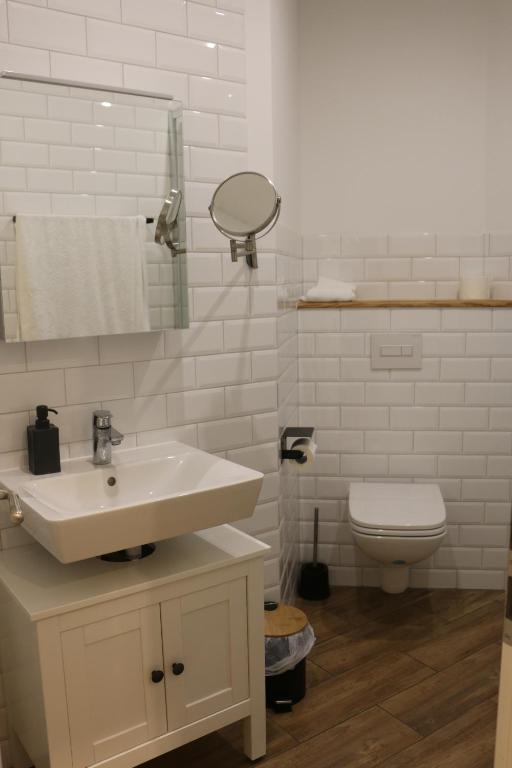 a white bathroom with a sink and a toilet at Gut Boltenhof in Fürstenberg