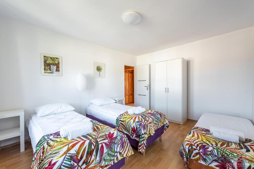 two beds in a room with white walls and wooden floors at Horyzont Apartamenty -Domek na Sosnowej z tarasem in Kołobrzeg