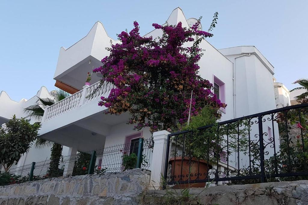 a white house with purple flowers on the balcony at Inviting 2-Bed House in Mugla in Gumusluk