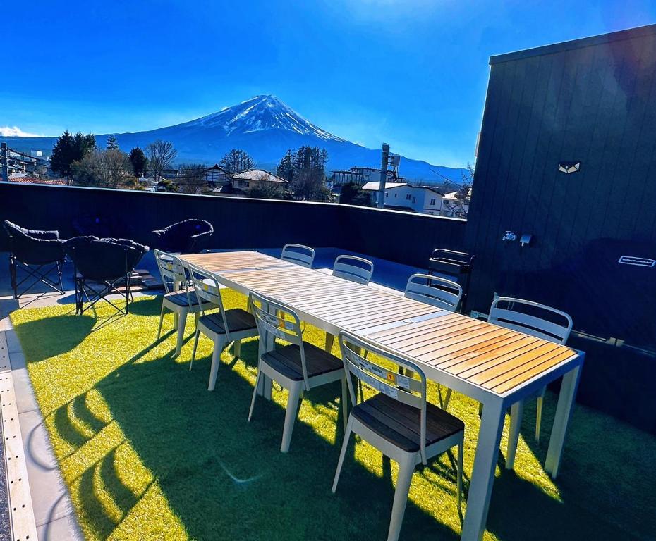 una mesa de madera y sillas en un balcón con una montaña en ヴィラ山間堂Panorama Villa BBQ Bonfire Fuji view Annovillas Sankando en Fujikawaguchiko