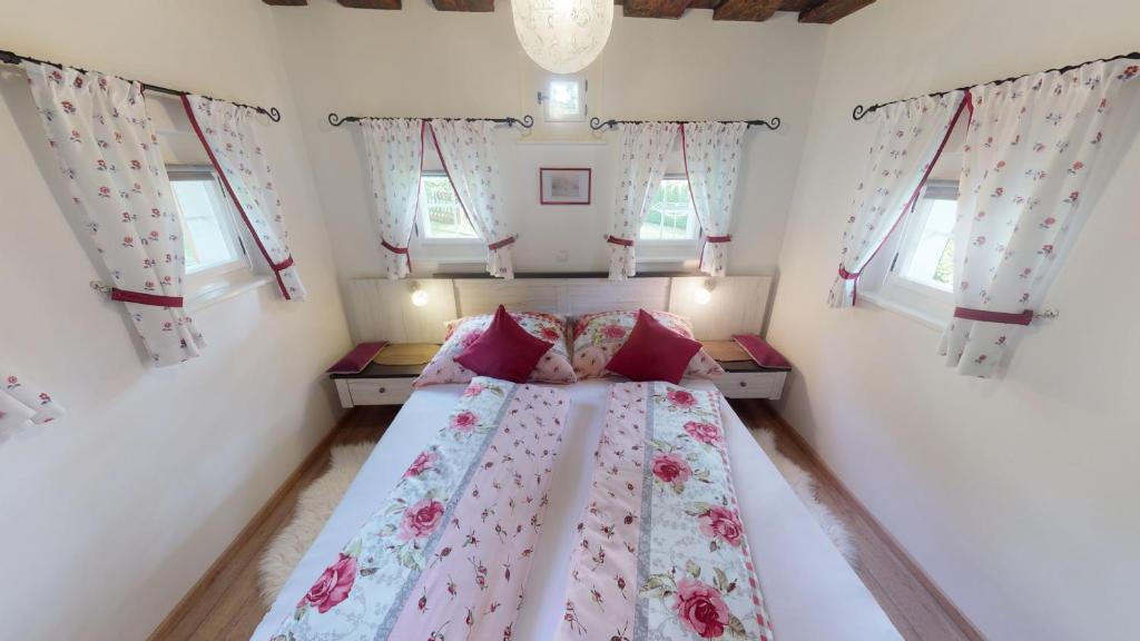 um quarto com uma cama com lençóis cor-de-rosa e janelas em Winzerhaus im Schilcherland em Steinreib