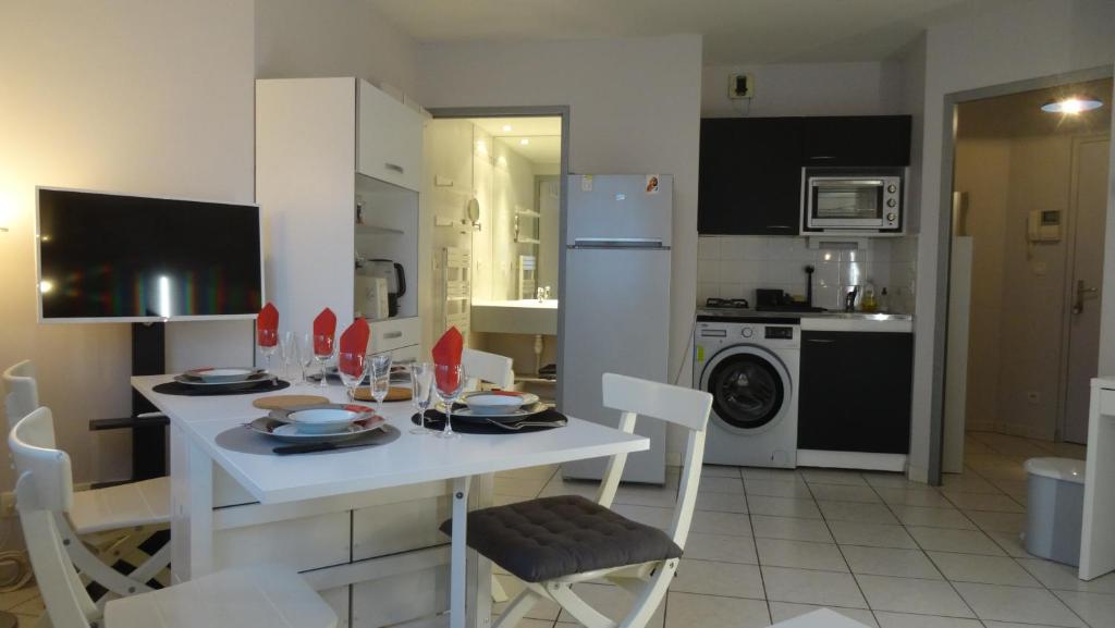 a kitchen with a white table and a white refrigerator at Appart T2 standing tout confort au calme - parking en option in Lyon