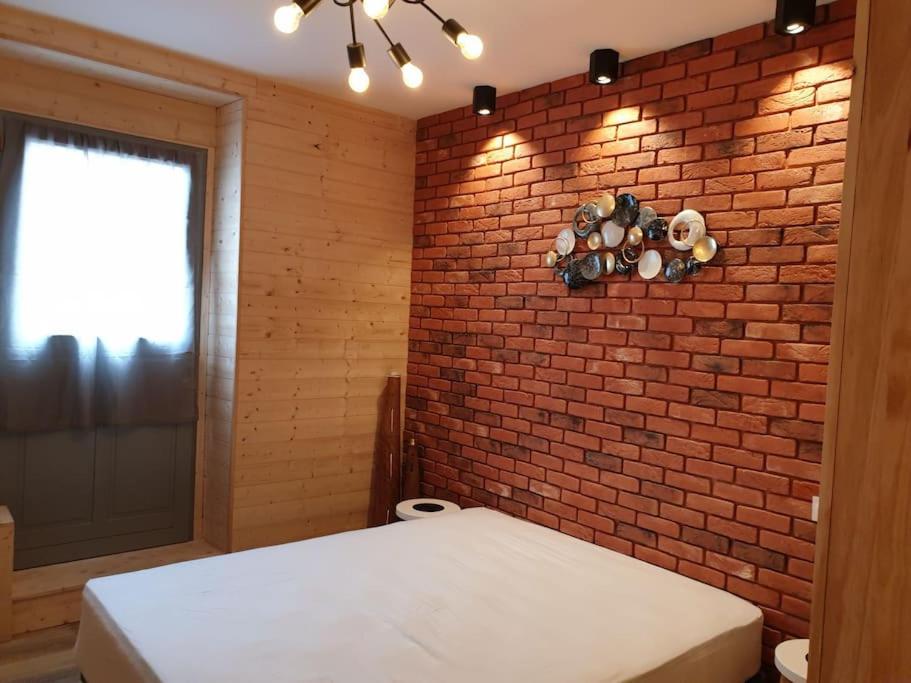 a brick wall in a room with a bed and a window at Les Iris Véranda Parcking in Le Mont-Dore