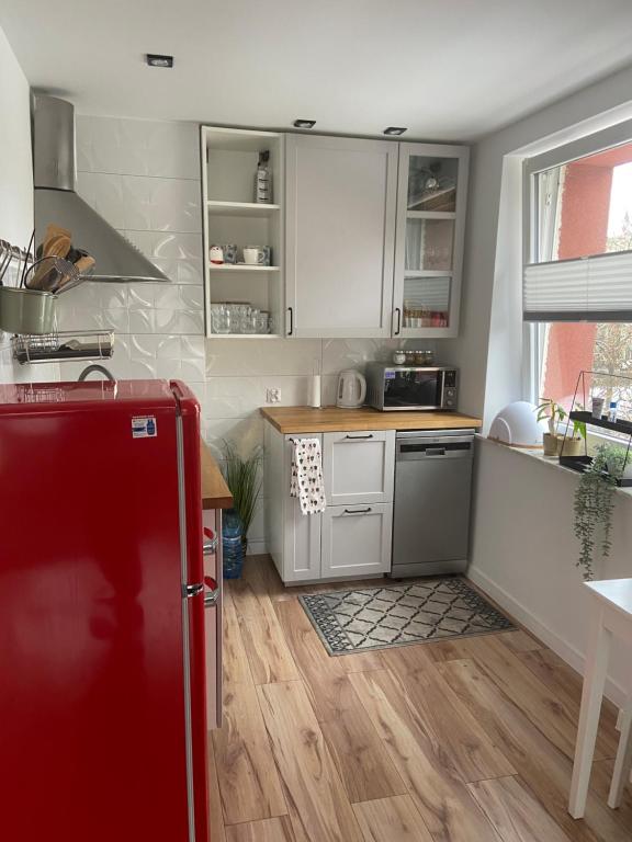 La cuisine est équipée de placards blancs et d'un réfrigérateur rouge. dans l'établissement Apartament w centrum miasta, à Suwałki