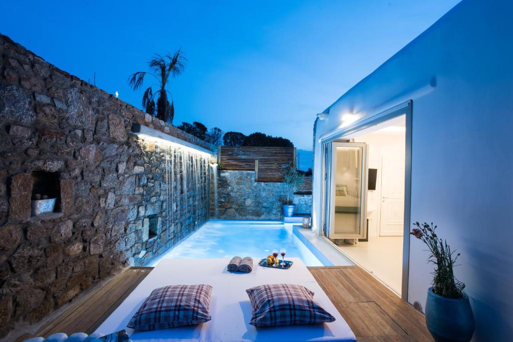 a swimming pool in a house with a stone wall at Mykonos Village in Ano Mera