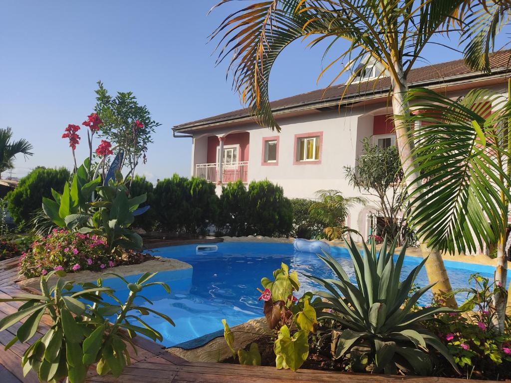 a swimming pool in front of a house with plants at Residence Jardin Tropical in Yaoundé