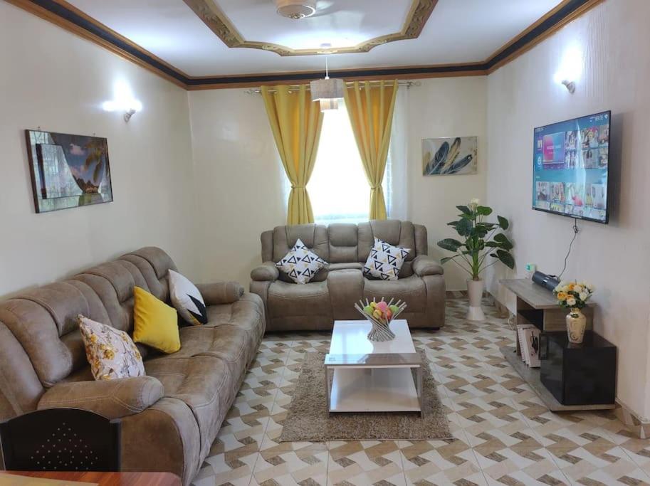 a living room with a couch and a table at Homely,Stylish Nyali 2BR Suite w/ Hot Shower WIFI in Mombasa