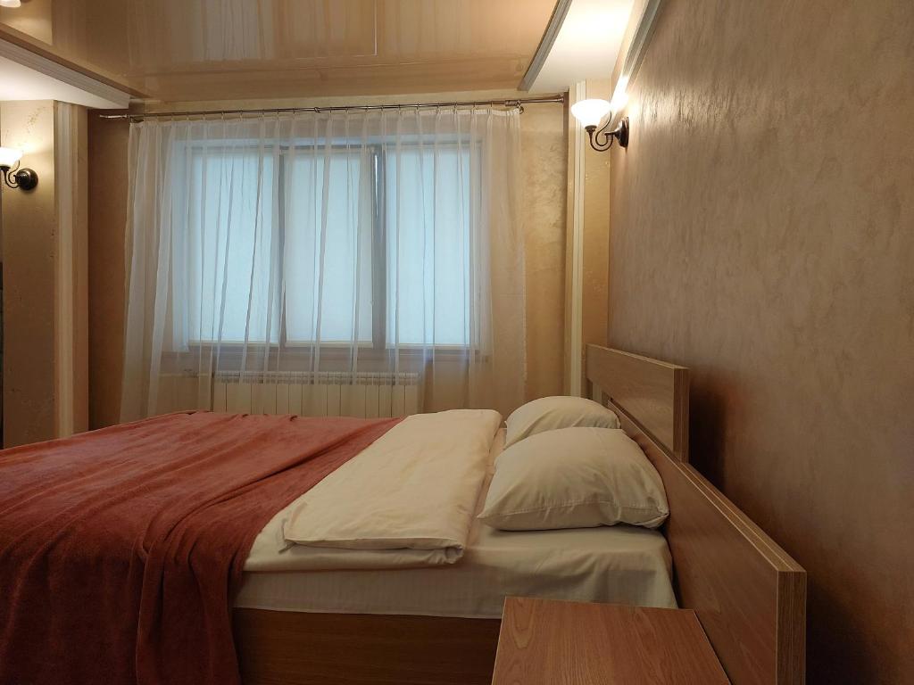 een kleine slaapkamer met een bed en een raam bij Затишна студія біля центру in Loetsk