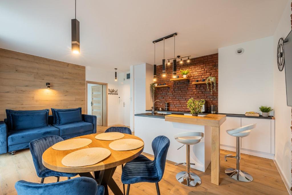 Una sala de estar con una mesa y un sofá azul. en Horyzont Apartamenty -Bałtycka2 - SAUNA & FITNESS - ŚNIADANIA, en Kołobrzeg