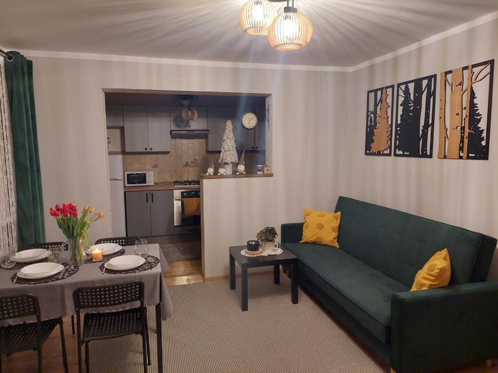 a living room with a green couch and a table at Domek nad potokiem in Kluszkowce