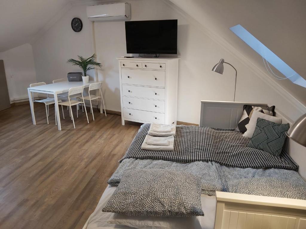 1 dormitorio con 1 cama y 1 mesa con TV en Kedves Apartman, en Pécs