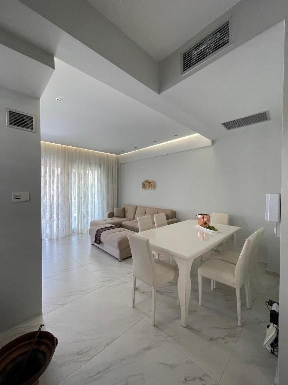 a living room with a white table and a couch at Villa Theodora in front of the sea in Hanioti