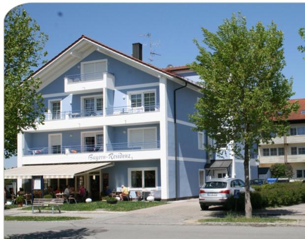 ein großes blaues Gebäude mit einem davor geparkt in der Unterkunft Appartementhaus Bayern Residenz in Bad Füssing