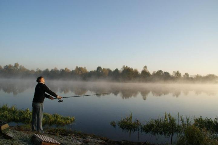 um homem a pescar num lago de manhã em Dom całoroczny nad Bugiem em Wasilew Szlachecki