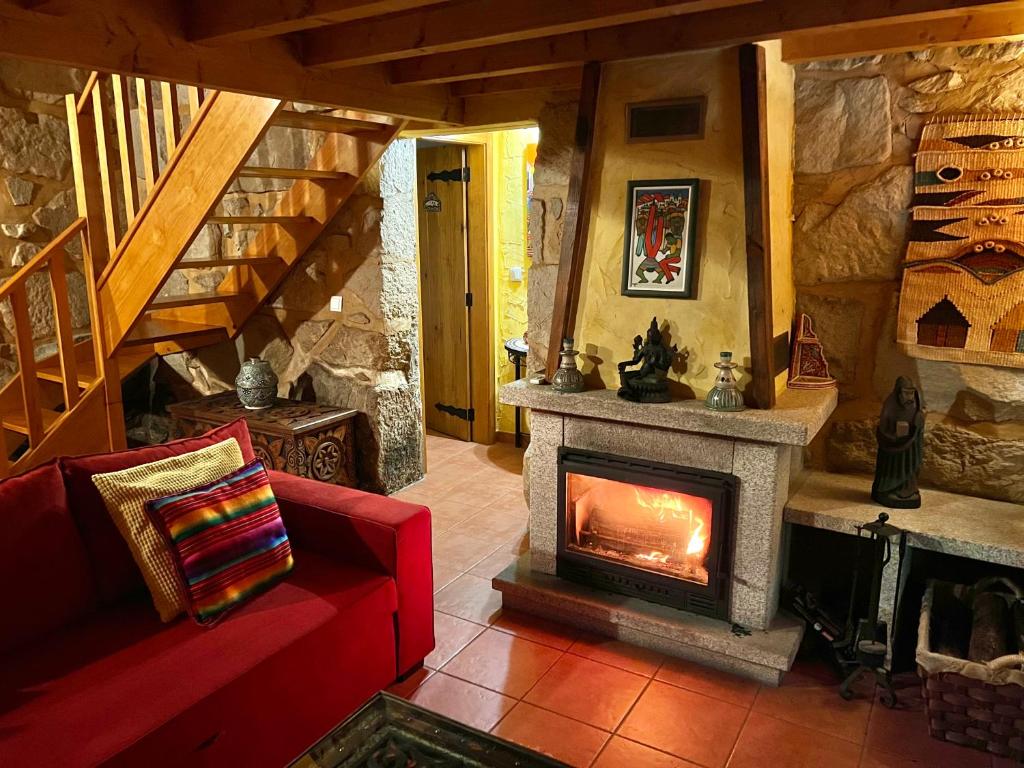 a living room with a fireplace and a red couch at Moinhos do Pisão in Povoa Dao