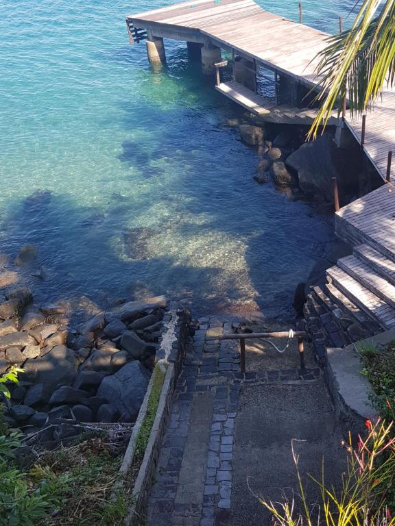 a dock in the water next to the ocean at Suítes home paraíso no norte in Ilhabela