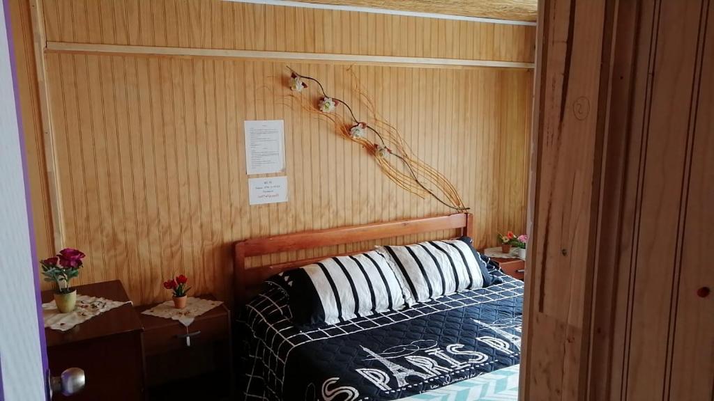 1 dormitorio con 1 cama con cabecero de madera en "Mi Hostal Tu Casa" Hostal Familiar SOLO EMPRESAS, TURISTAS y VIAJEROS, en Puerto Montt