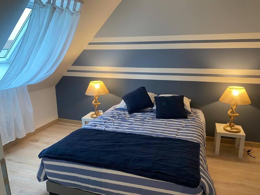 une chambre avec un lit aux murs bleus et deux lampes dans l'établissement Entre terre et mer, à Écault