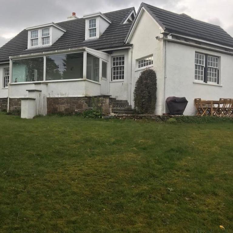 a white house with a porch and a yard at Craigievern Holiday Cottage in Drymen