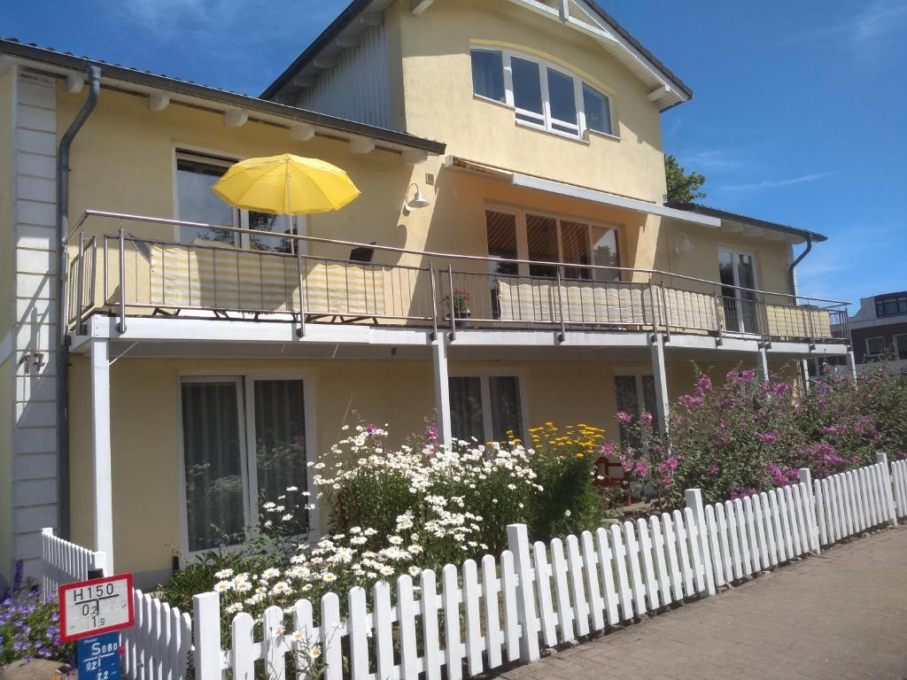 Cette maison jaune dispose d'un balcon avec un parasol jaune. dans l'établissement Haus Malve Dahme, à Dahme