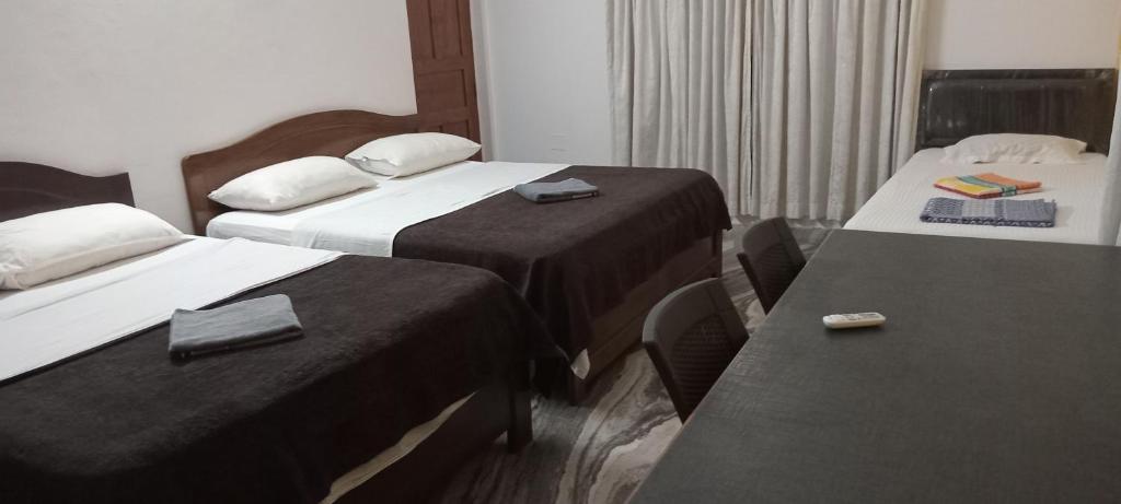 Habitación de hotel con 2 camas y mesa en Shalom Guest House, en Panaji
