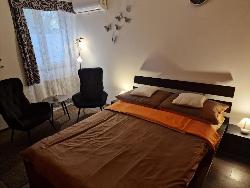 a bedroom with a bed with two chairs and a window at Tóvárosi apartman in Tata