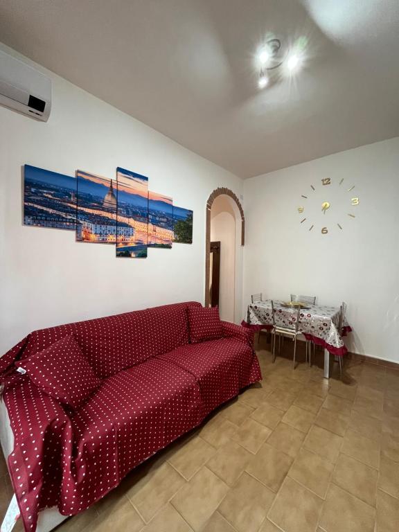 a red couch in a living room with a clock on the wall at House vittone venaria reale 2 in Venaria Reale