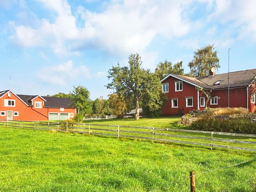 BrålandaにあるHoliday home BRÅLANDA VIの赤い家屋2棟と柵のある農場