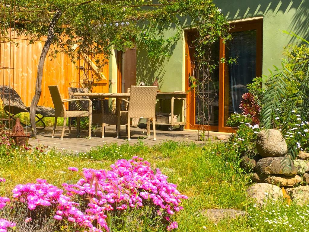 un jardín con mesa, sillas y flores en La rose bleue (2) en Olmeto