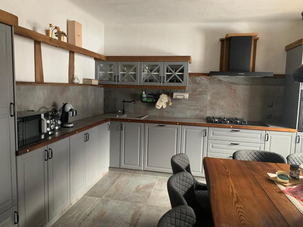 a kitchen with white cabinets and a wooden table at Hiša Pod gorami II****-house with wellness in Kranjska Gora