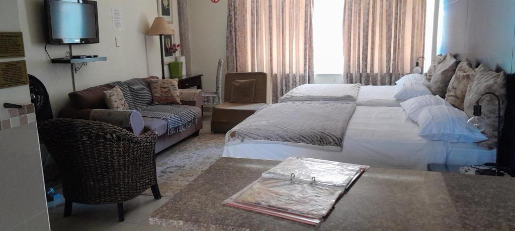 a bedroom with a bed and a couch and a table at Durban Shores Holiday Apartments in Durban
