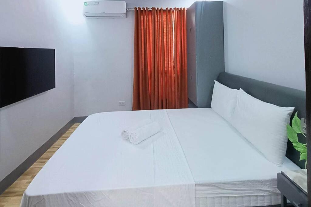 1 cama blanca grande en una habitación con ventana en 5 - Cabanatuan City's Best Bed and Breakfast Place en Cabanatuan