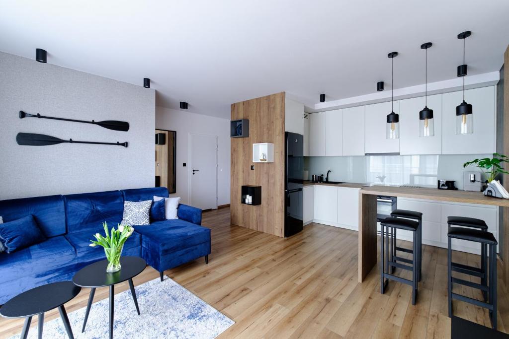 a living room with a blue couch and a kitchen at Apartament Marynarska Aquapark in Reda
