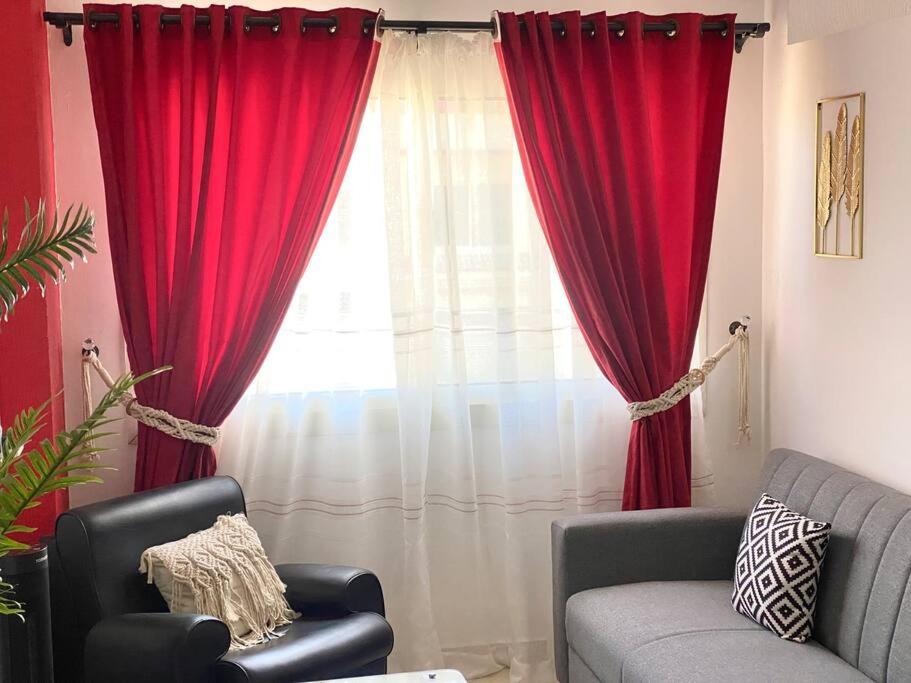 New cozy apt. on the promenade في الغردقة: غرفة معيشة مع ستائر حمراء وأريكة