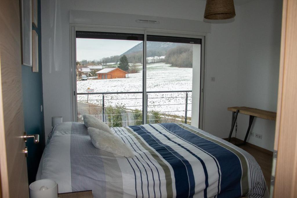 ein Schlafzimmer mit einem Bett und einem großen Fenster in der Unterkunft A l’orée du Vuache 