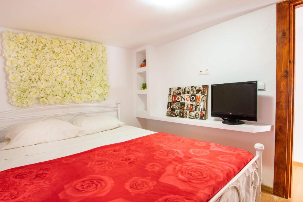 a bedroom with a bed with a red blanket and a tv at Maria House in Karpathos Town