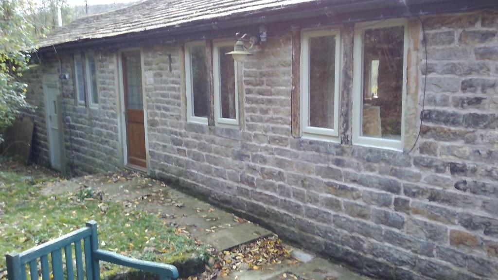 una casa de ladrillo con un banco delante de ella en Millstone cottage, en Oldham
