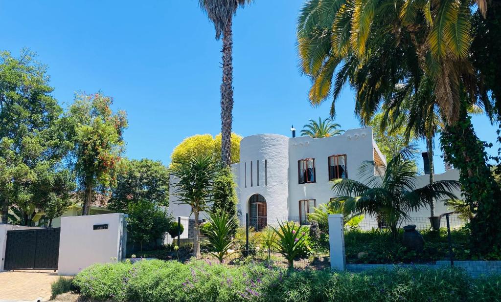 a white house with palm trees in front of it at Little fern self catering in George