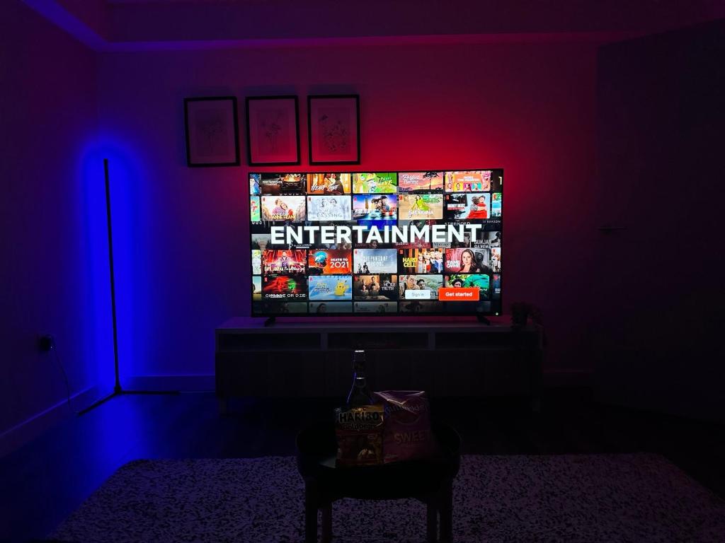 a television in a dark room with a blue and red light at Large 65 Inch TV Full Kitchen Long-Stay Ready in Liverpool