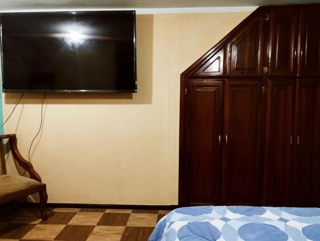 1 dormitorio con TV de pantalla plana grande en la pared en Bonito Departamento Sur de Quito, en Quito