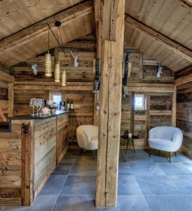 Cette chambre dispose de murs en bois, de deux chaises et d'une table. dans l'établissement Chalet de L'Ours Blanc, à Saint-Gervais-les-Bains