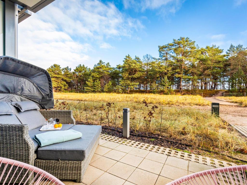 eine Terrasse mit einem Sofa, Stühlen und einem Feld in der Unterkunft FeWo Prora - Sunny in Binz