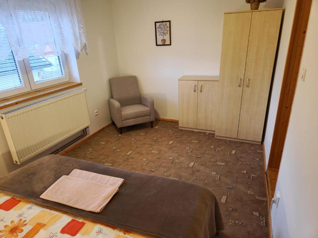 a bedroom with a bed and a chair and a window at Apartmány Grobarčík in Zuberec