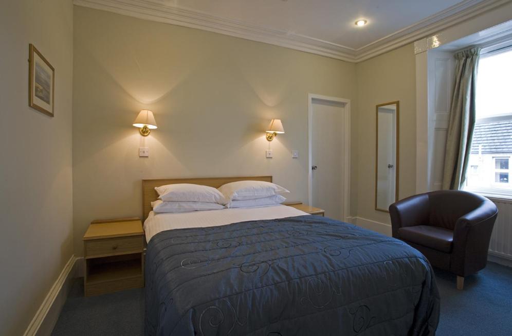 um quarto de hotel com uma cama e uma cadeira em St Clair Hotel em Thurso