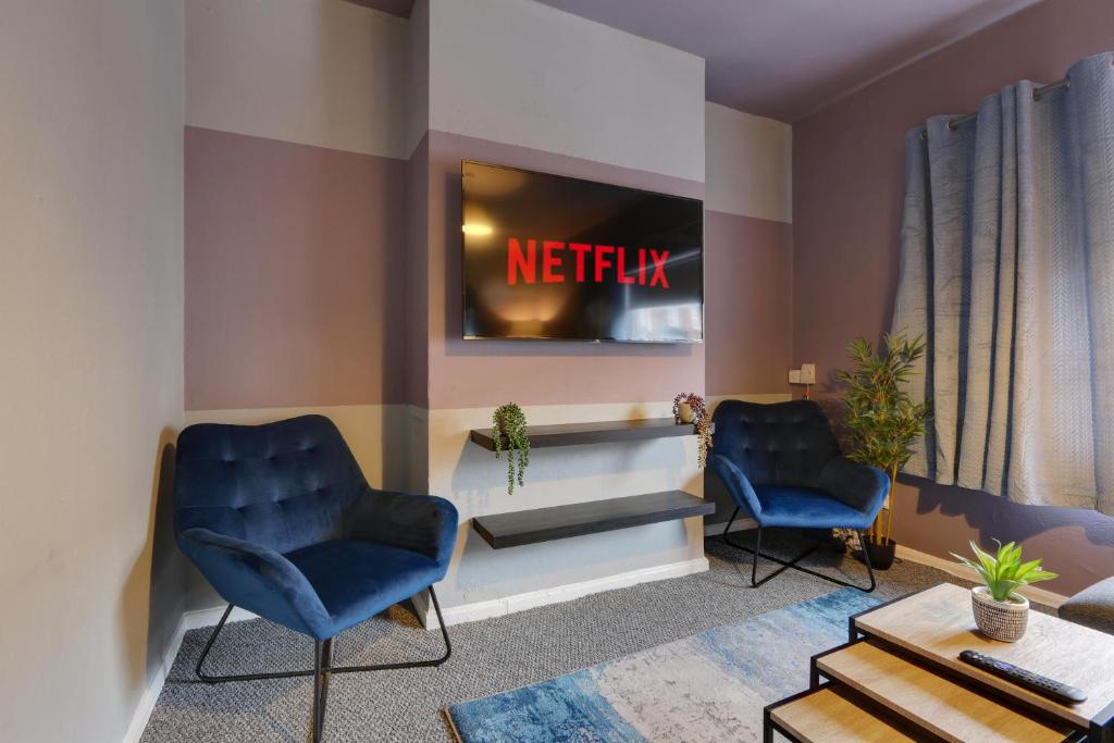 a waiting room with two blue chairs and a television at Stylish base on Abbeydale Road in Sheffield